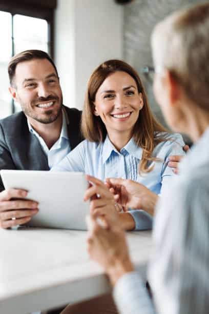 Young happy couple talking to their real estate agent on a business meeting in the office