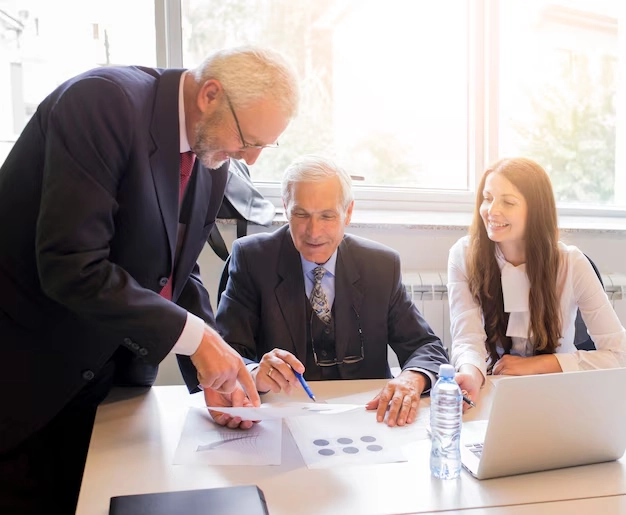 Senior angel investors reviewing financial services documentation with professional advisor in office