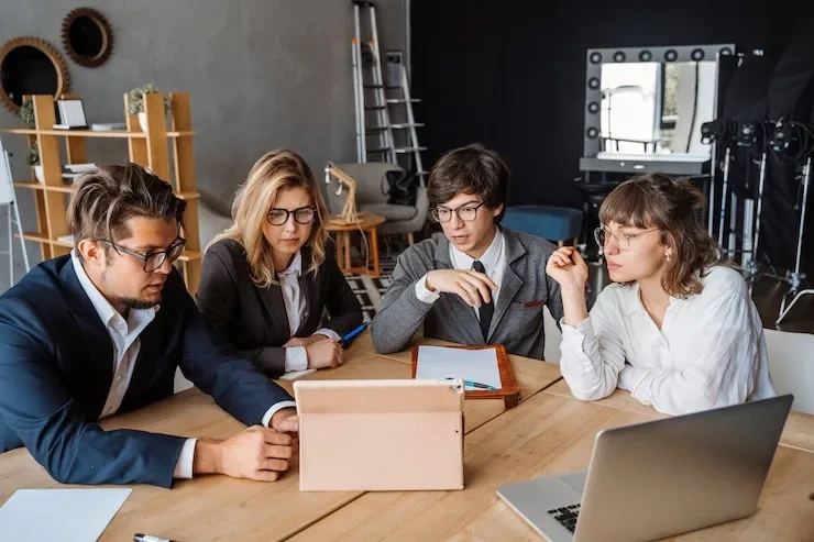 Four professionals analyzing intellectual property royalty management services at creative workspace