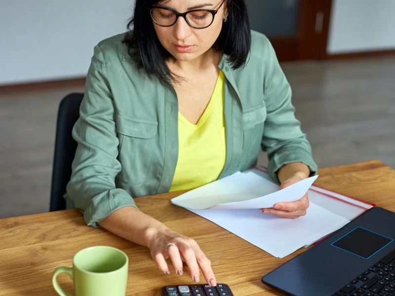 Professional female accountant for day traders using calculator while reviewing trading documents