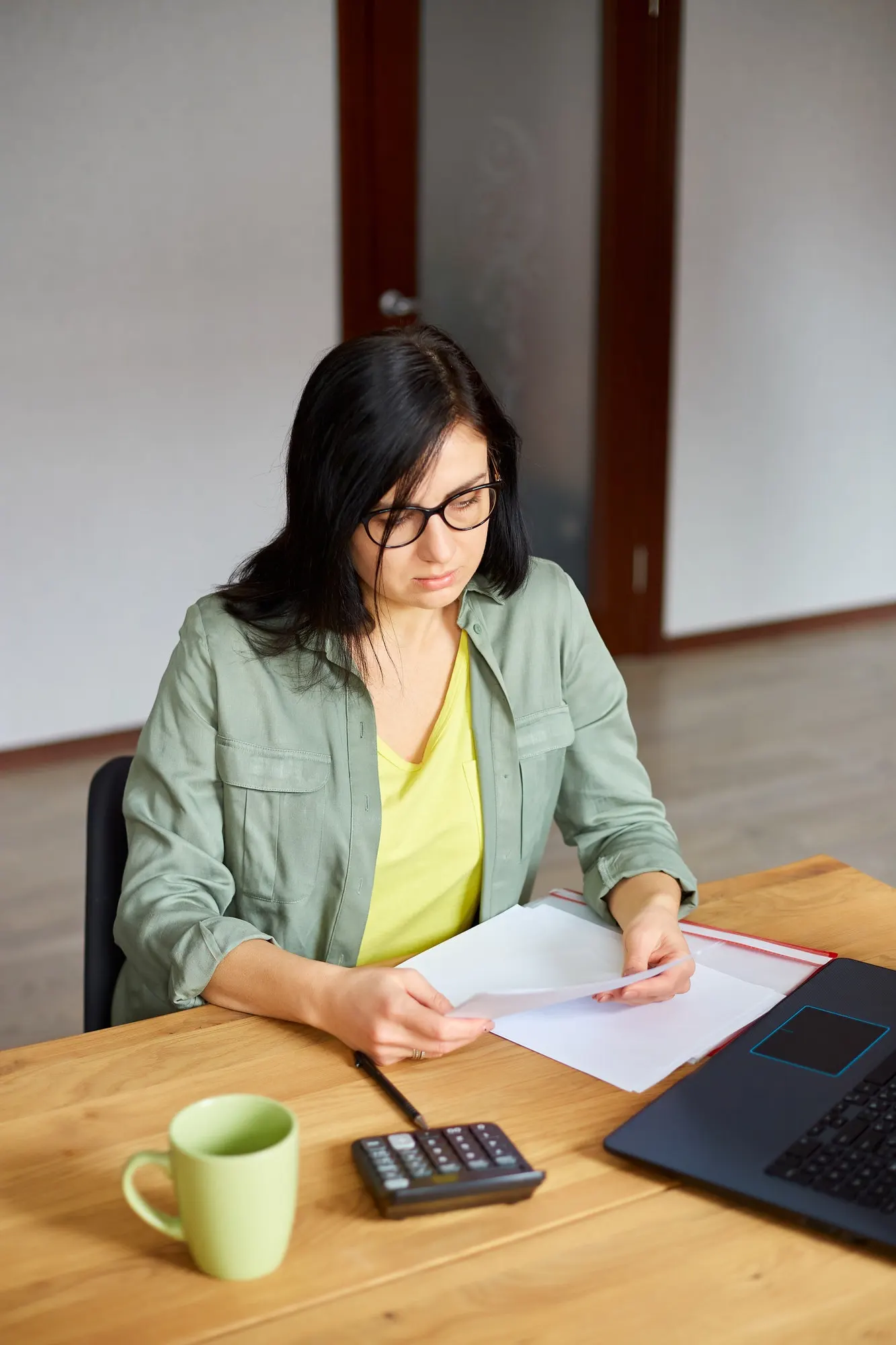 Person working on international tax planning documents beside a laptop and calculator on the desk.
