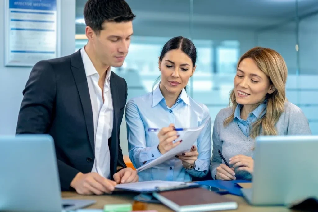Corporate advisors work collaboratively on client documentation in bright office setting