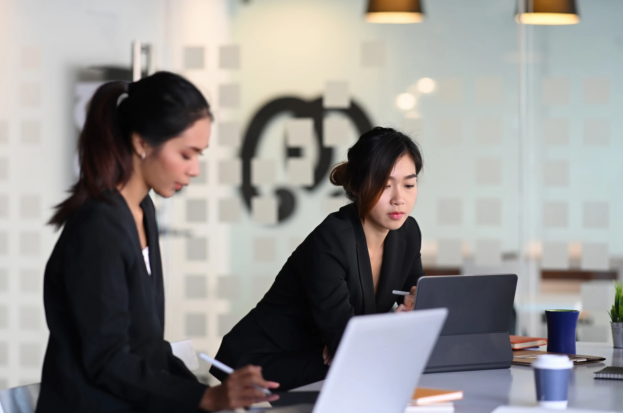 Two professional accountants for day traders collaborating on laptops in modern office workspace