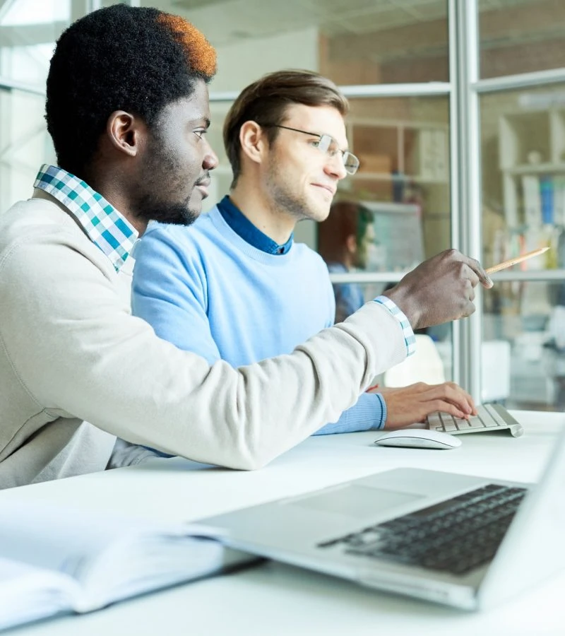 Two professional accountants for day traders collaborating on laptop analyzing trading data together