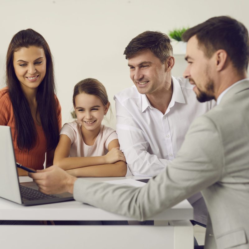 Two office men pointing to a laptop screen for a young girl and an office girl