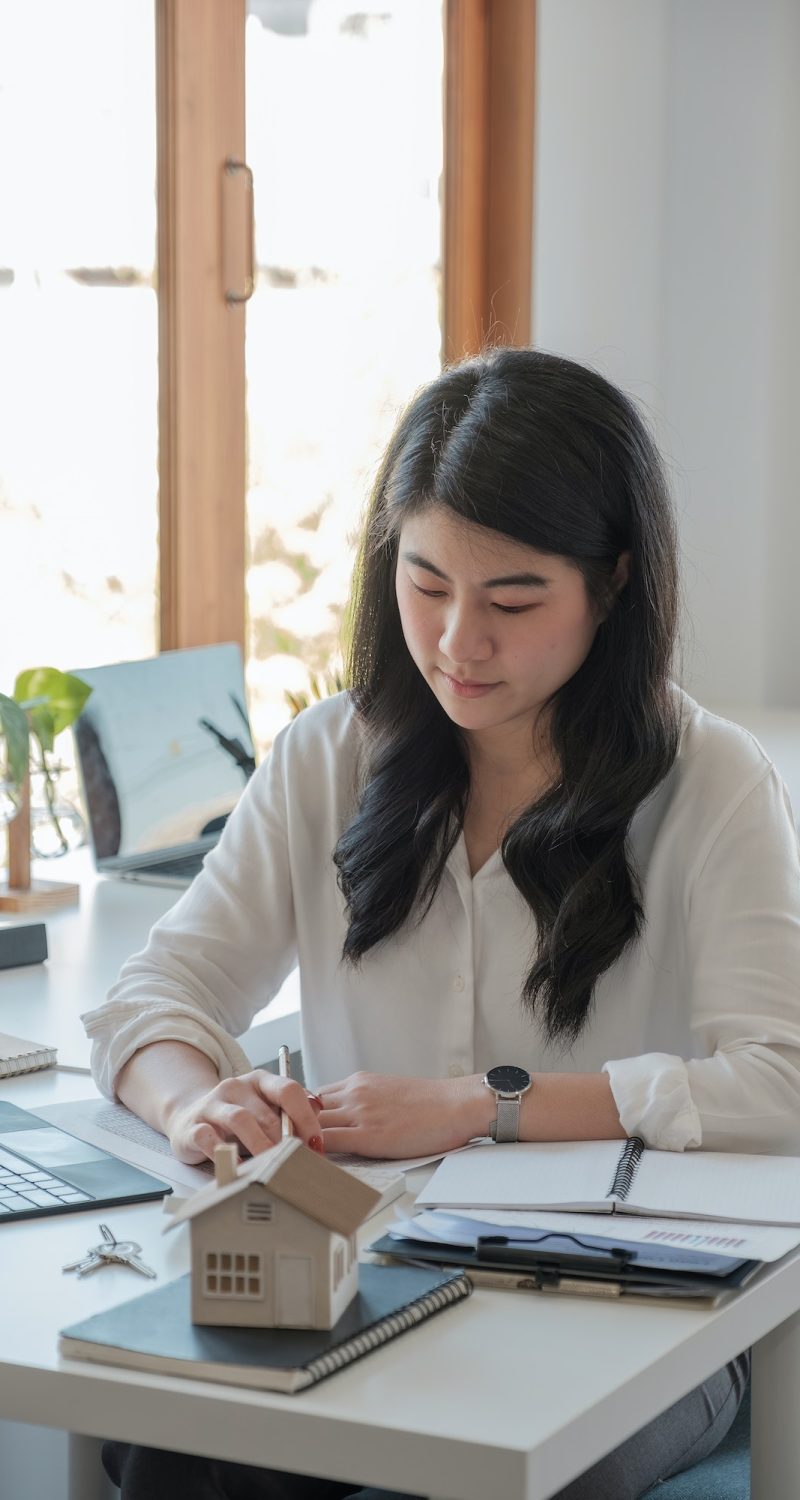 Business asian woman using calculating interest, taxes and profits to invest in real estate and home