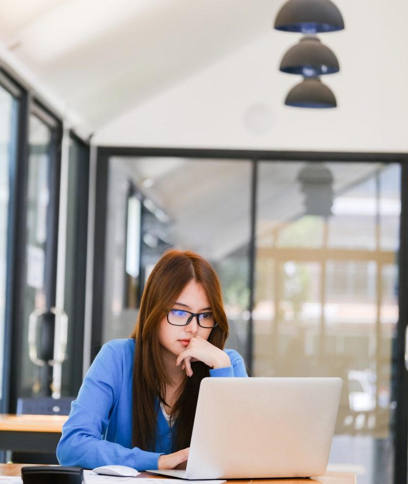 Young girl in a blue dress using a laptop for bookkeeping for farm work