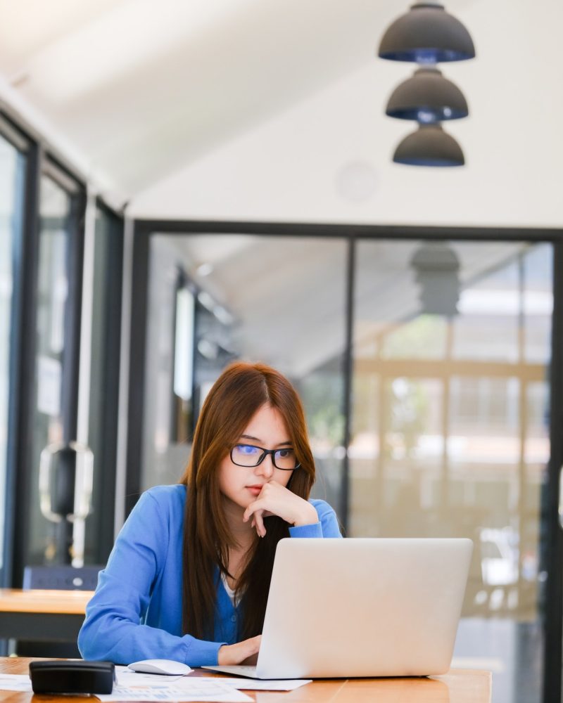 Young girl in a blue dress using a laptop for bookkeeping for farm work