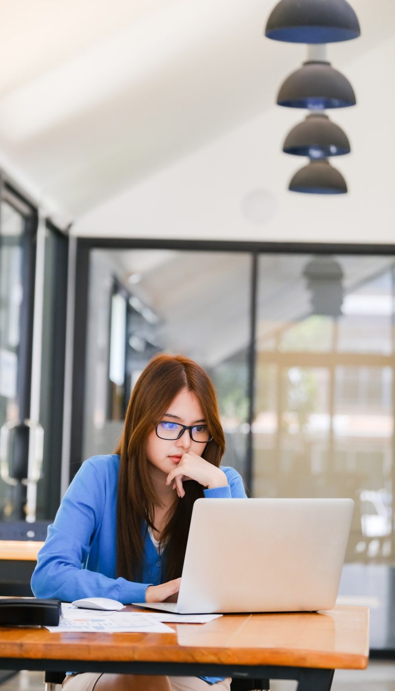 Young girl in a blue dress using a laptop for bookkeeping for farm work