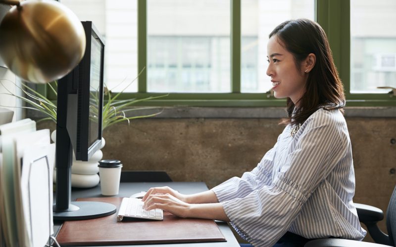 Chinese woman working at a computer in an office, side view,  Bookkeeping for Small Business, Corporate Tax Services, Accountants for Medical Professionals