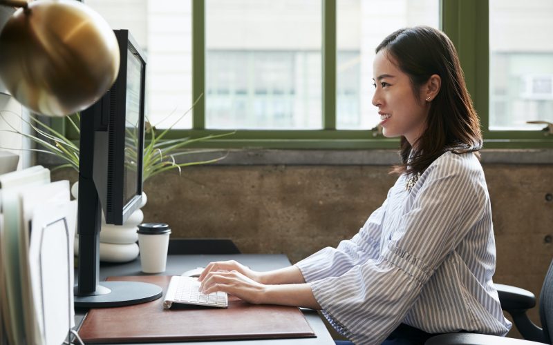 Chinese woman working at a computer in an office, side view Chinese woman working at a computer in an office as an accountant and bookkeeper