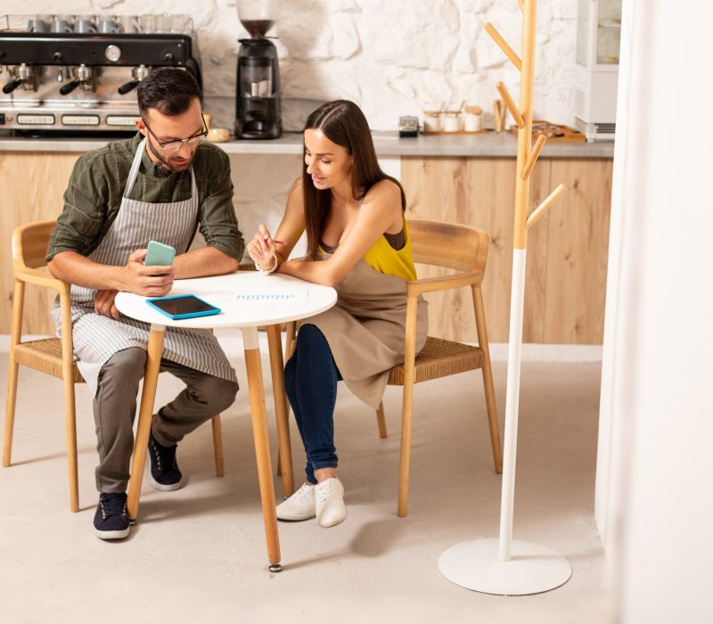 Husband helping wife with accounting after opening cafeteria Boy teaching accounting and bookkeeping to the girl