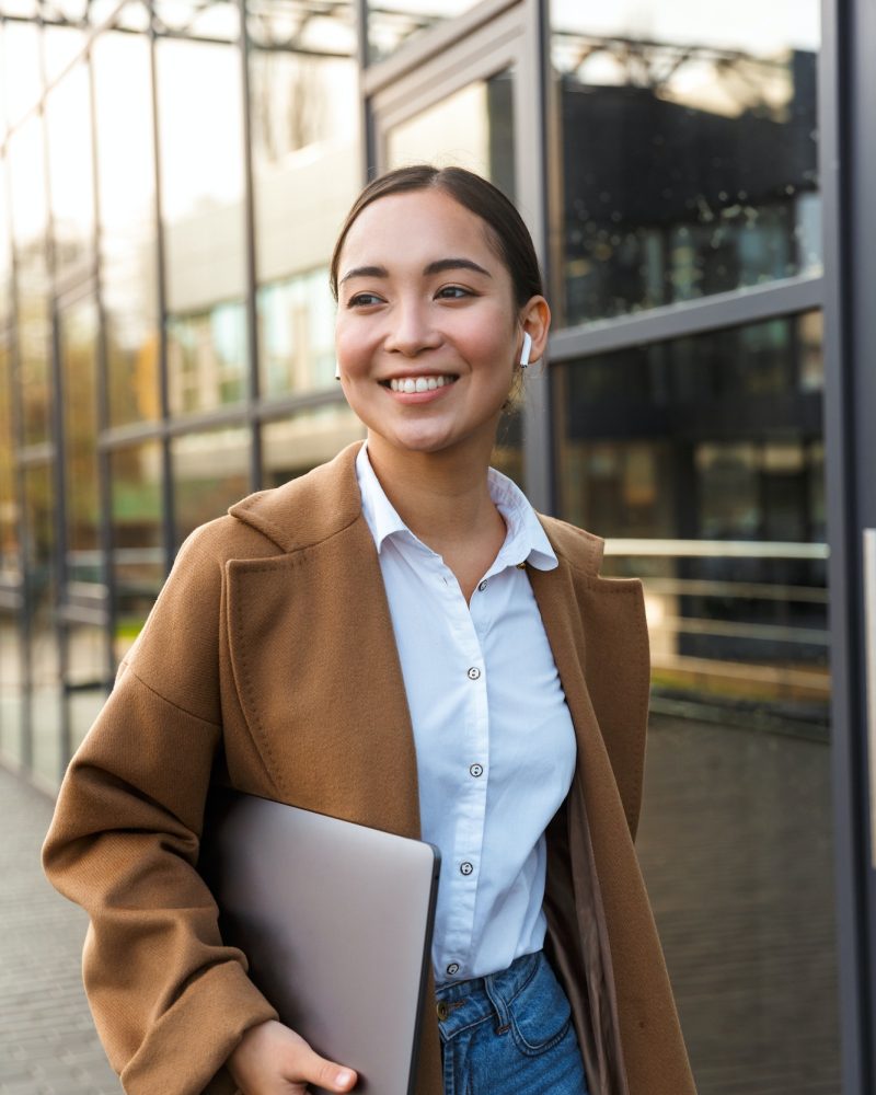 Image of young brunette asian woman holding laptop while walking, Tax Planning for Business, Tax Planning for Business Owners, Year-End Tax Planning