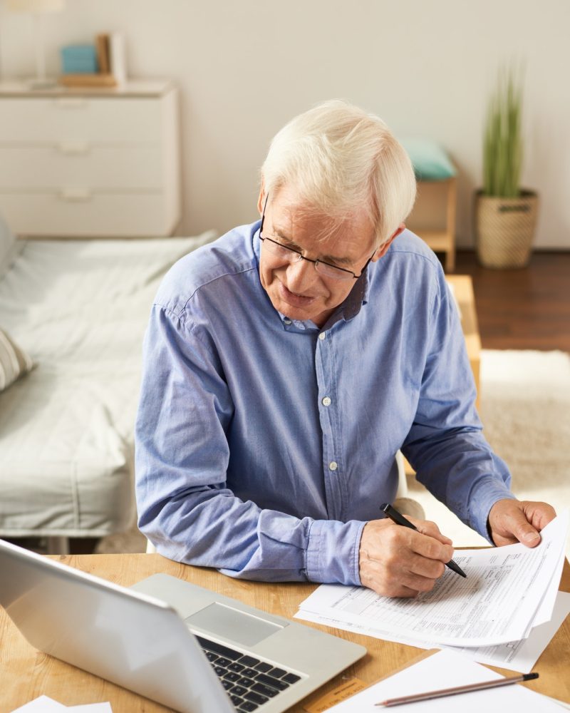 An older accountant doing accounting for movies at his home