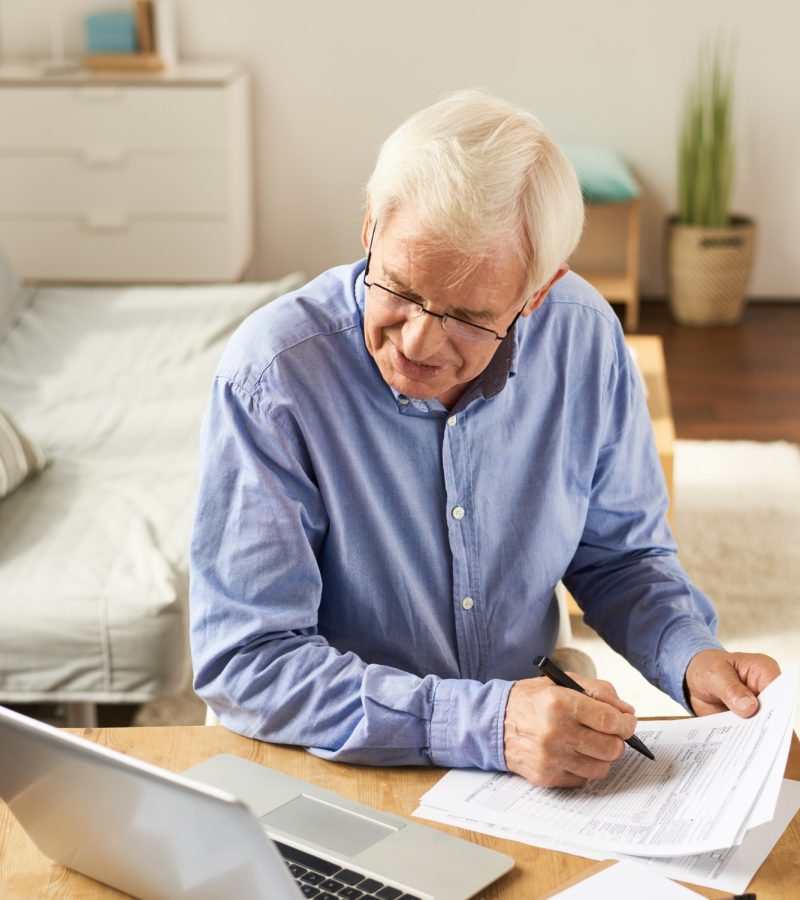 An older accountant doing accounting for movies at his home