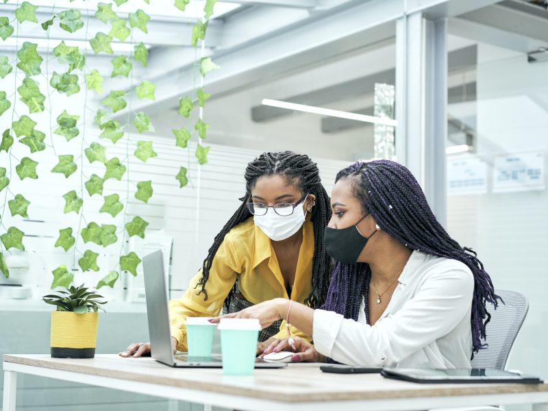 Two young women in the office, working together from the computer. Bookkeepers for real estate agents working together