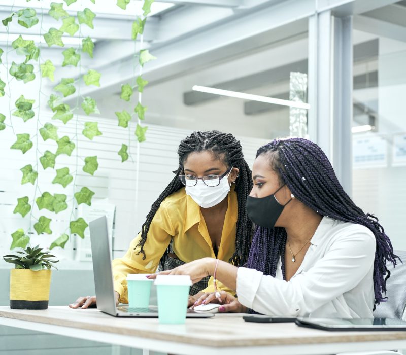 Two young women in the office, working together from the computer. Bookkeepers for real estate agents working together