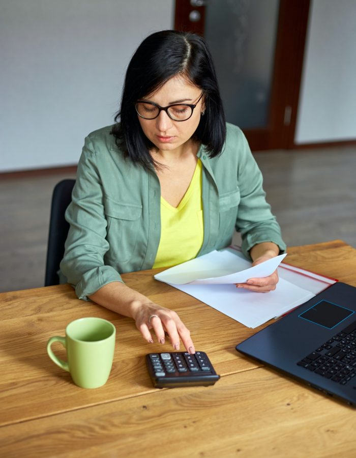 Woman accountant sit calculate expenses on calculator at wooden table, modern workplace, Small Business Accountant, Accountants For Hairdressers, Accountants For Estates