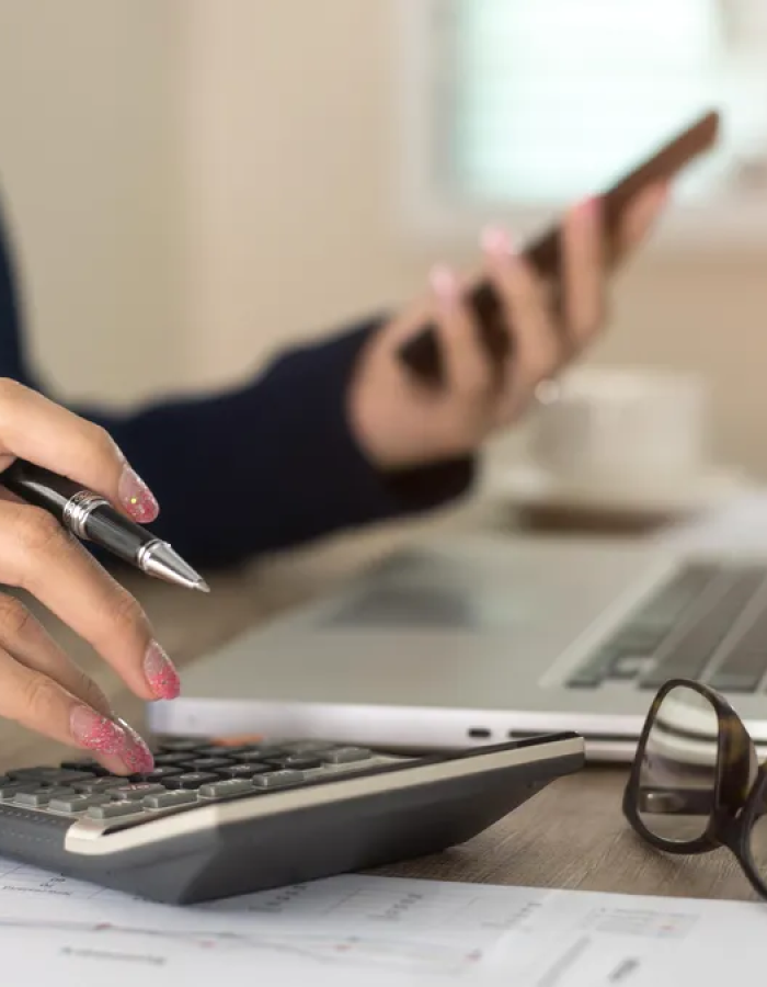 Girl using phone while calculating data on a calculator