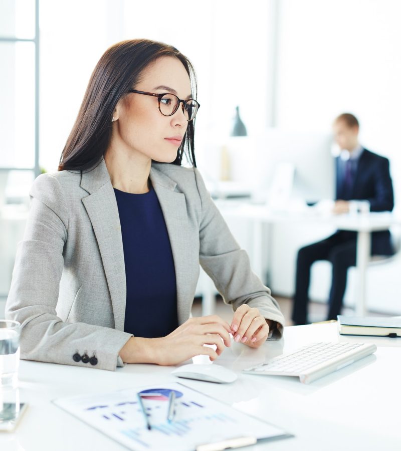 A beautiful working girl with glasses, wearing a coat, in the office