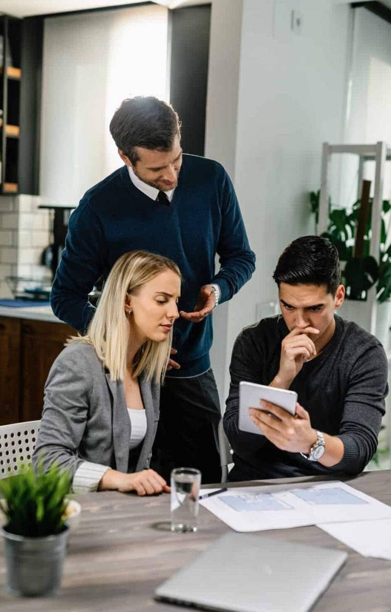 Young couple feeling uncertain while using digital tablet on a meeting with their insurance agent at home.