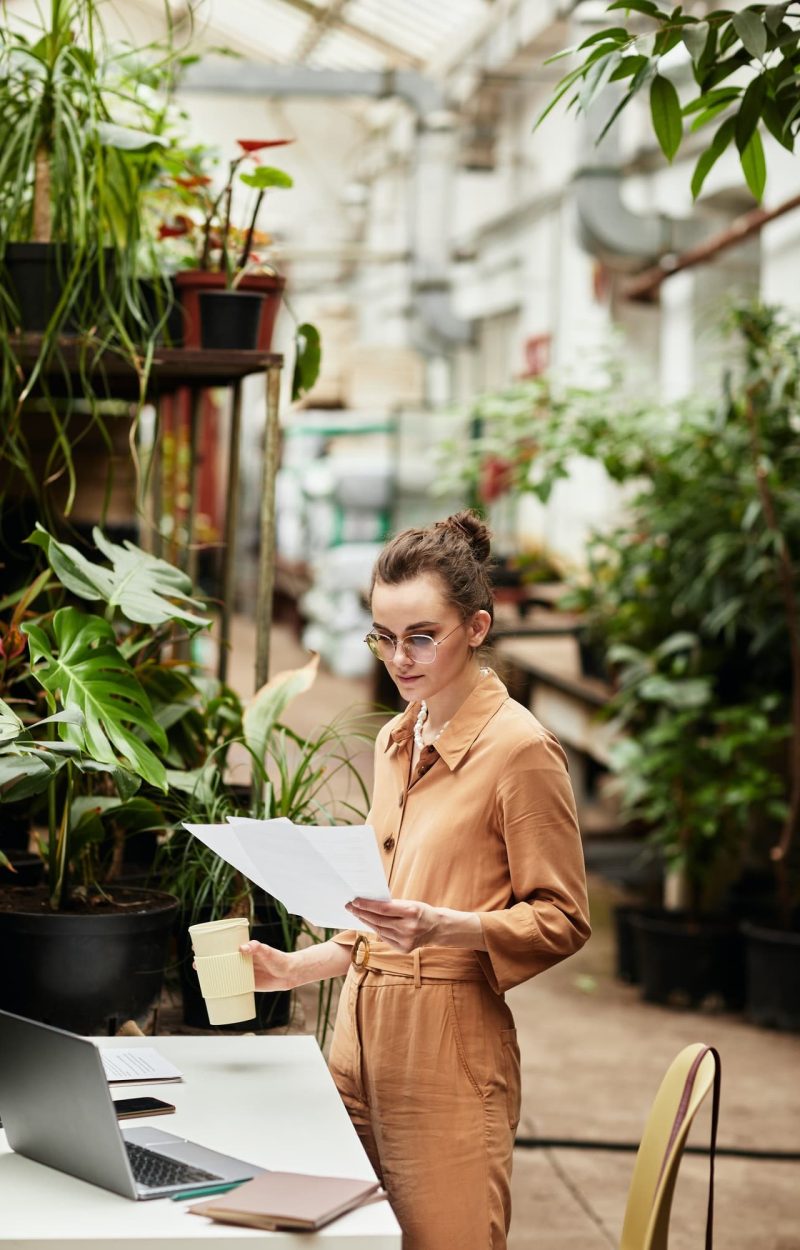 Young female accountant of contemporary orangerie or florist shop