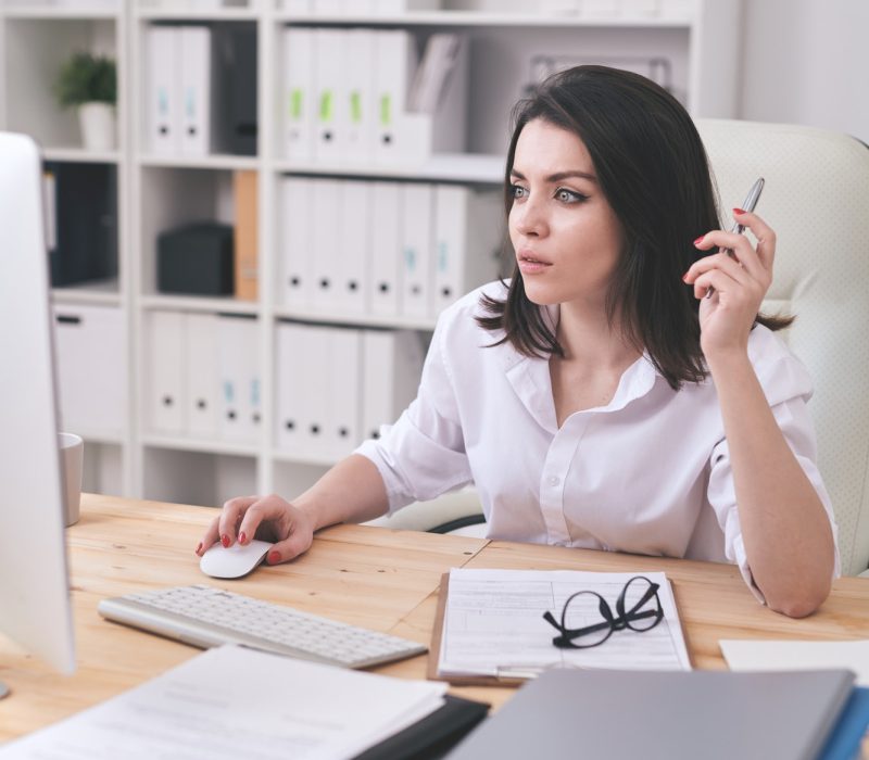 Young female accountant or financial analyst sitting in front of computer for bookkeeping services