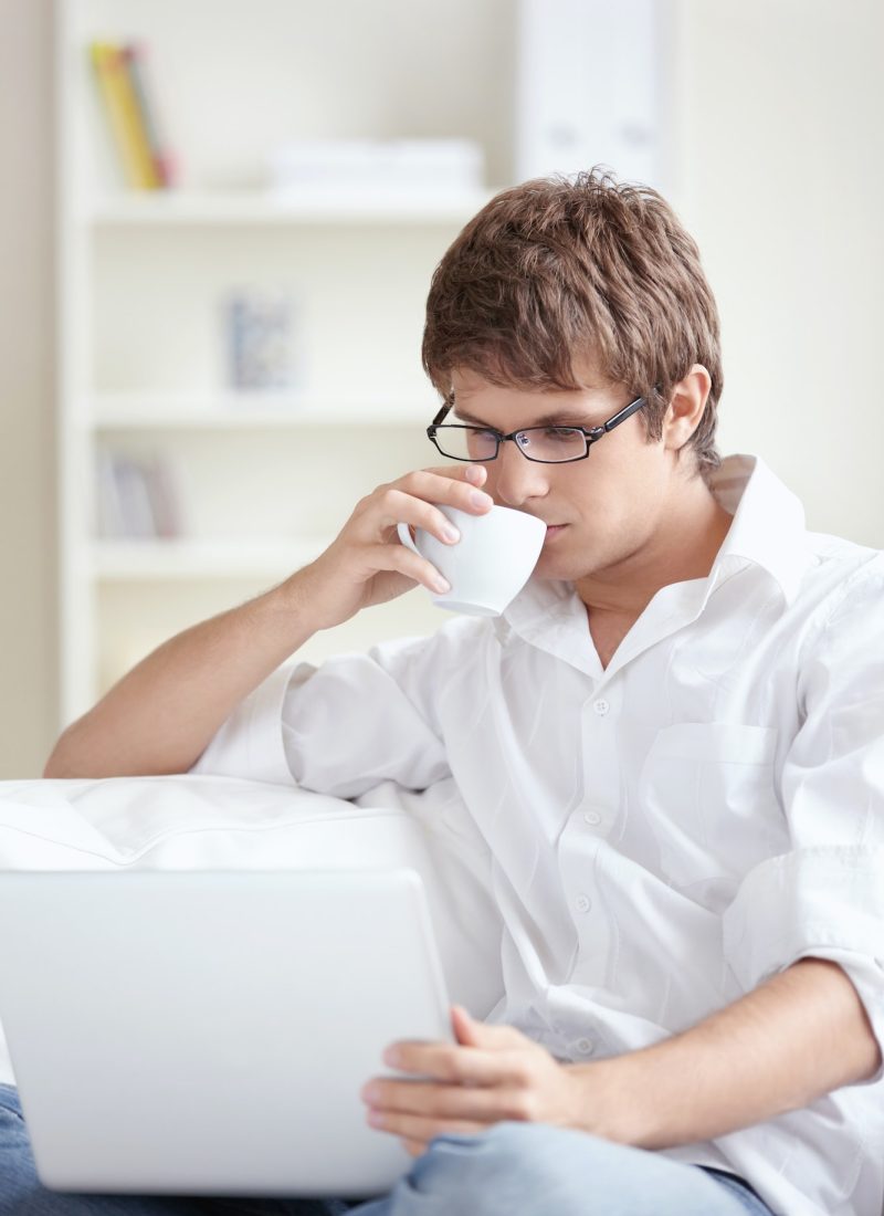 Young accountant and bookkeeper drinking tea and using a laptop